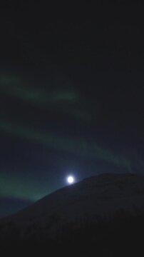 Timelapse view of green aurora with full-moon dancing over Malangen Fjord