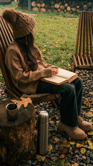 Woman reading a book outdoors on a fall day, enjoying autumn