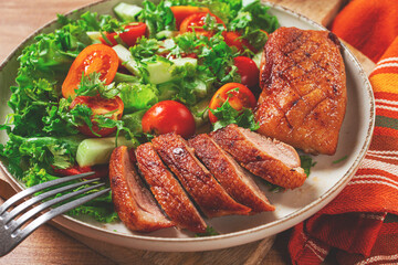 Delicious grilled duck breast served with fresh garden salad and cherry tomatoes at a rustic dining table