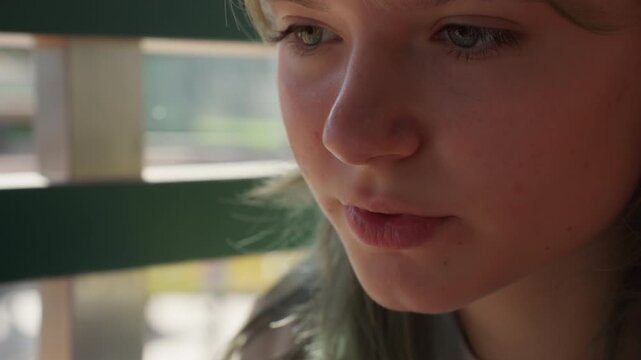 Beautiful young girl with dyed hair eating french fry in fast-food restaurant, showing profile close-up view of face as teenager girl enjoy meal with thoughtful expression