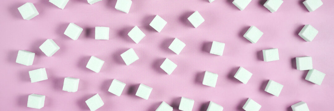 Geometric arrangement of white sugar cubes on pastel pink background in diagonal pattern.