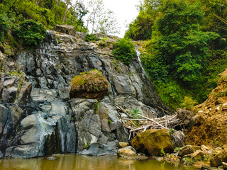 Rock cliff with small water flow in the mountain slope river in Yogyakarta area, Indonesia