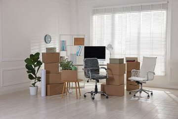 Moving day. Cardboard boxes, computer and furniture in office