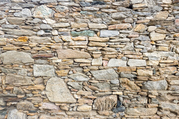 Old stone wall texture made of irregular natural rocks, perfect for rustic architecture, background design, and construction material concepts.