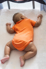 Baby sleeping peacefully in crib wearing orange onesie