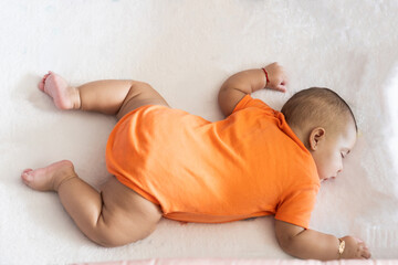 Baby sleeping peacefully wearing orange bodysuit