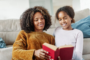 Mother and daughter reading a book on sofa at home