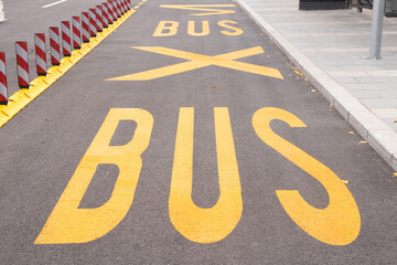 Yellow road markings at bus stop and safety fluorescent striped railing lane dividers on city street