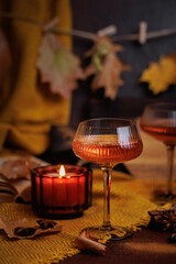 Rose wine glass with candle on table decorated with leaves and spices in warm fall setting