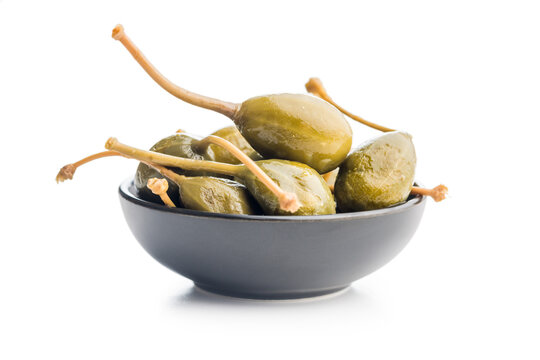 Pickled capers berries in bowl isolated on white background.