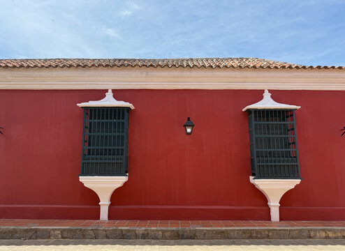  Colonial architecture facade with a vibrant red wall on a street in the old town - Coro, Venezuela
