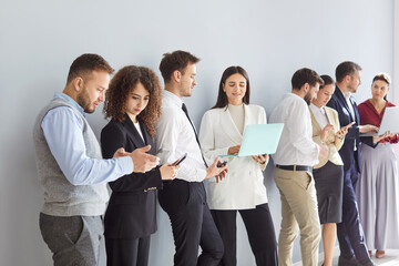 Diverse business team applicants waiting standing, businesspeople in row, queue for job interview, holding phone, laptop using, hr employment meeting, employment visit, choosing new workers 