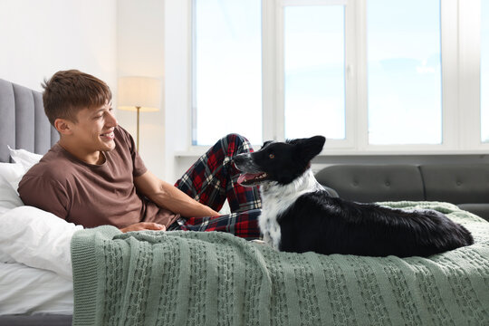 Pet friendly hotel. Man and his cute dog on bed indoors