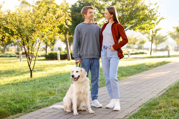 Happy couple with their adorable golden retriever dog in park