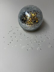 Silver Christmas bauble with golden glitter on neutral background