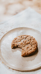 A cookie is on a white plate with a bite taken out of it