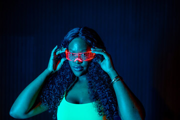 Young woman exploring augmented reality with glowing cyberpunk spectacles at night © Alberto