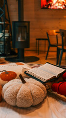Cozy autumn scene with pumpkins, a book, and a fireplace in the background