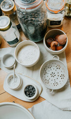 A table with a variety of bowls and jars of ingredients, including flour, sugar