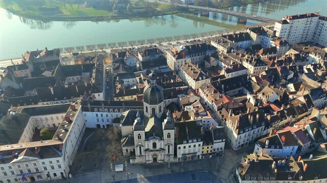 Time lapse drone footage showing baroque church and old town with waterway behind under clear morning light with moving clouds 