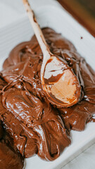A spoon is scooping chocolate from a pan