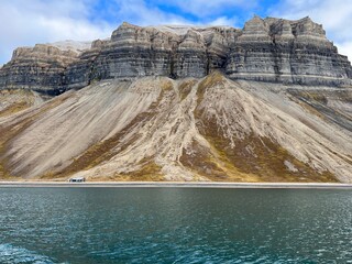 Small cabin is situated beside the ocean with a stunning mountain in Nordre Isfjorden, Spitsbergen, Svalbard