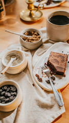 A plate of brownie with a fork on it sits on a table with a white cloth