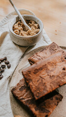 A plate of brownies sits on a table with a bowl of brown sugar and a spoon