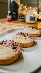 Three small pastries with pink frosting and green sprinkles on top