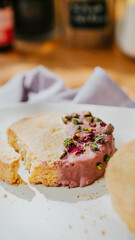 A slice of cake with pink frosting and green nuts on top