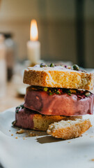 A stack of three different colored pastries with a candle in the middle