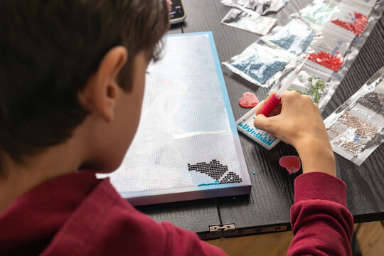 Young boy assembling diamond art mosaic at home &ndash; screen-free creative hobby, mindful craft for children, fine motor skills, mental wellness, art therapy at home