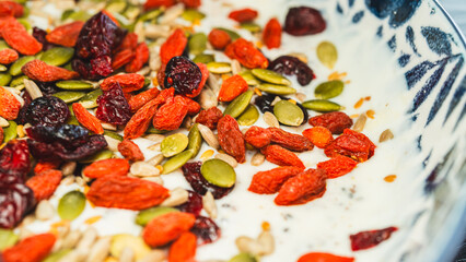 Beautiful healthy yogurt bowl with pumpkin seeds, goji berries, chia seeds, dried cranberries and other superfoods. Nutritious breakfast or snack for wellness lifestyle.