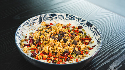 Beautiful yogurt bowl with crunchy granola, chocolate pieces, pumpkin seeds, goji berries and chia seeds. Perfect healthy breakfast or snack with a tasty indulgence.