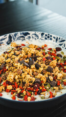 Beautiful yogurt bowl with crunchy granola, chocolate pieces, pumpkin seeds, goji berries and chia seeds. Perfect healthy breakfast or snack with a tasty indulgence.