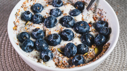 Healthy yogurt bowl topped with fresh blueberries and mixed seeds. Nutritious breakfast or snack for a balanced diet and active lifestyle. Simple and delicious.