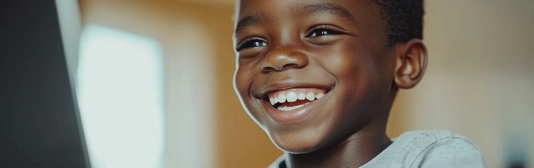 Fototapeta premium A joyful child smiling brightly while engaging with a computer, capturing the essence of happiness and curiosity in a playful moment.