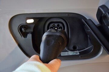 A woman connects a charger to an electric car