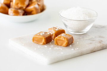 A close up of pieces of caramel with rock salt on a small marble slab.