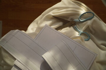 Sewing pattern, fabric, and scissors, garment cutting process close-up, sewing project