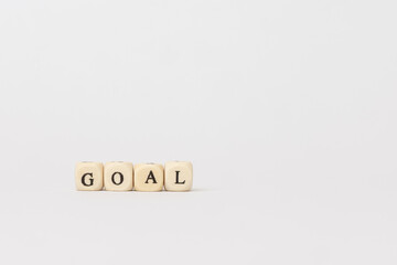 Wooden blocks spelling the word goal on a minimalistic background, symbolizing ambition and achievement in personal and professional life. copy space