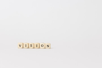 Wooden blocks spelling vision on a minimalistic background, emphasizing clarity and focus in personal and professional development. copy space