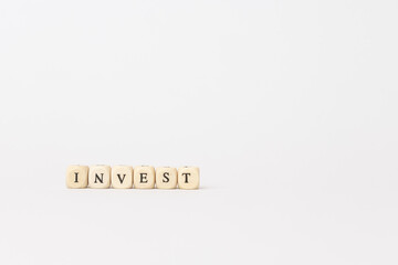 Wooden blocks spelling the word invest on a minimalistic white background, symbolizing finance and investment concepts with copy space. copy space