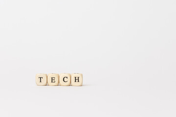 Wooden blocks spelling tech on a minimalistic white background, representing innovation and modern technology concepts in finance. copy space