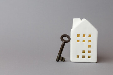 White ceramic house model with key beside it, symbolizing finance and technology concepts related to home ownership and investment opportunities. copy space