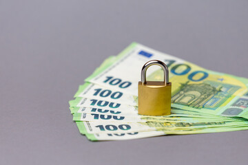 Stack of hundred euro banknotes with a golden padlock symbolizing financial security and protection in the world of finance and technology. copy space