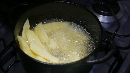 POV: French fries in a rustic pan. Someone frying potatoes. Frying fries in a pan.