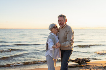 Keep moving. Romantic senior mature couple dancing together on beach outdoor recreation. Happy smiling family retired man woman husband wife having fun enjoying time together. Family moment love care