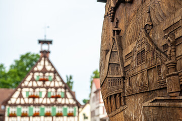 Reliefschnitzerei eines Fachwerkhauses, im Hintergrund unscharf das Original-Fachwerkhaus altes Rathaus  in Uhlbach 