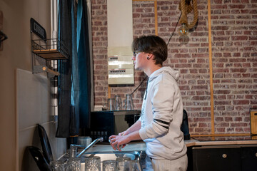 jeune homme en jogging faisant la vaisselle dans sa cuisine